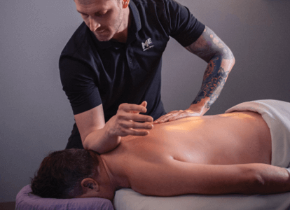 Therapist pressing down as he massages client lying on table. 
