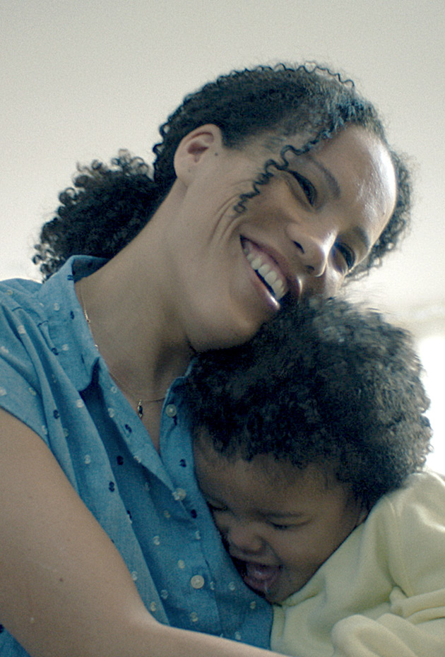 Woman smiling brightly as she embraces her child. 