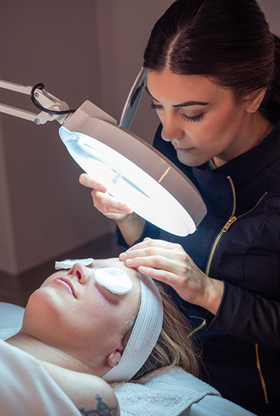Close-up of esthetician as she looks down during an acne clarifying facial. 
