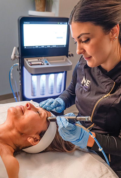 Esthetician performing hydrafacial treatment. 