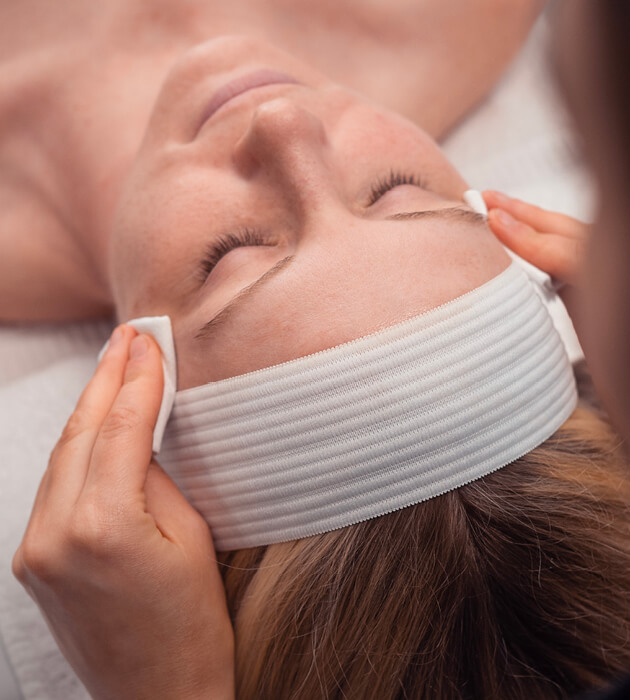 Woman with eyes closed during facial service by esthetician. 