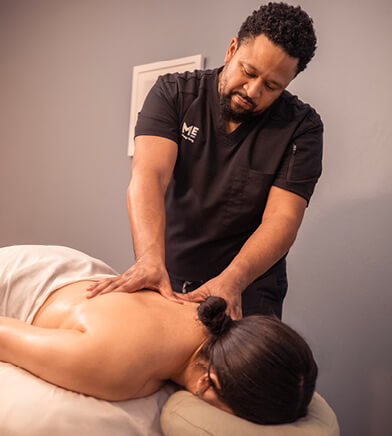 Woman lying down at therapist massages her back. 