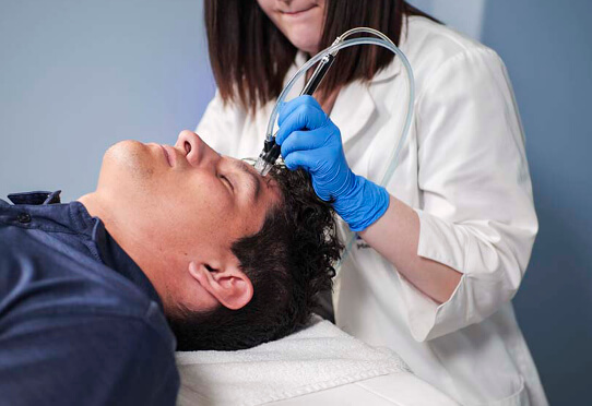 Man laying down while receiving a microderm treatment from esthetician