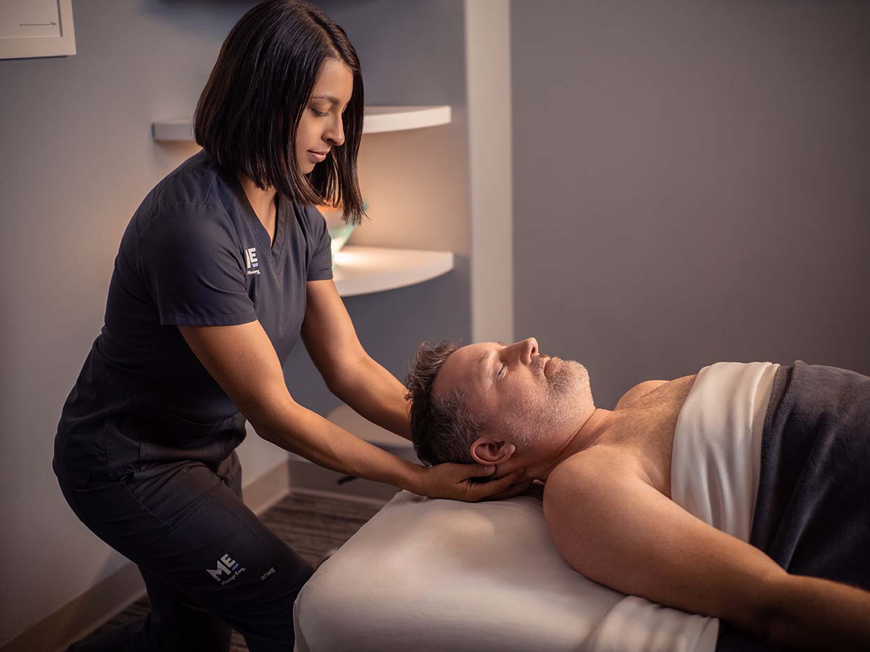 Man lying on table with eyes closed as he receives a massage. 
