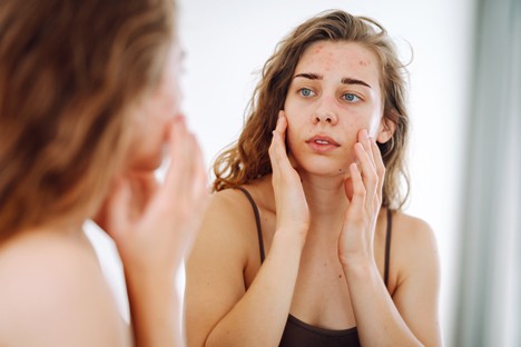 Woman checking her face in the mirror. 